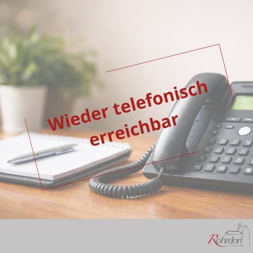Schreibtisch mit einem schwarzen Tischtelefon, daneben ein Notizblock und ein Stift. Über dem Bild steht in roter Schrift „Wieder telefonisch erreichbar“. Unten rechts befindet sich das Logo der Gemeinde Rohrdorf.