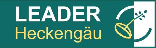 Logo der LEADER-Region Heckengäu Logo der LEADER-Region Heckengäu. Auf dunkelgrünem Hintergrund steht in großen weißen und gelben Buchstaben ‚LEADER Heckengäu‘. Rechts ist das stilisierte LEADER-Symbol mit einem gelben Blatt beziehungsweise einer Ähre dargestellt.